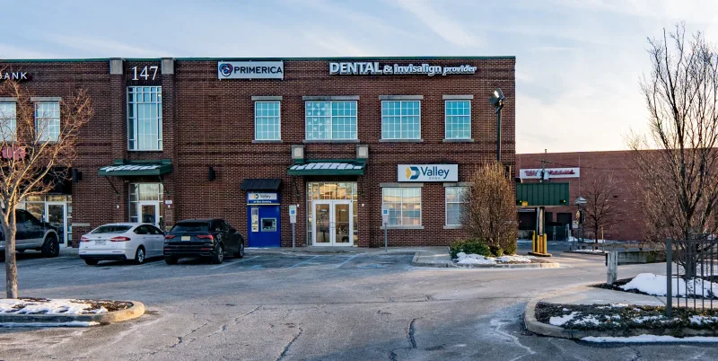 A small brick building with signs for a dental office and a bank.