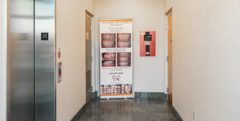 Roll-up banner in hallway displays dental advertising with smiling people.