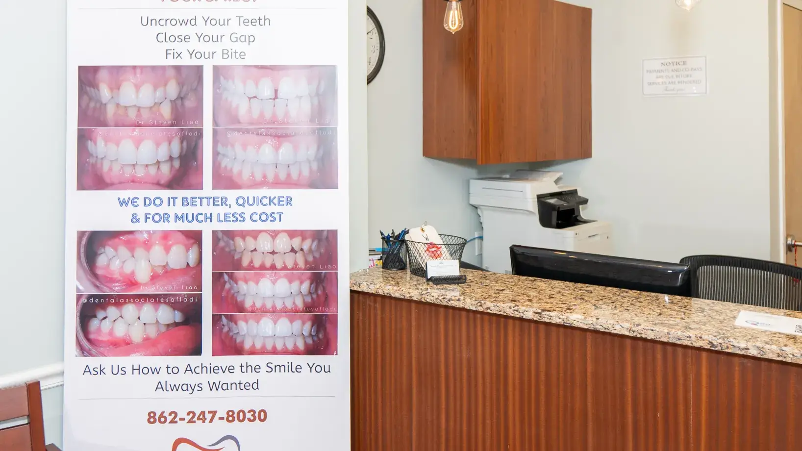 A dental clinic's reception area with a banner showing before-and-after teeth alignment photos.